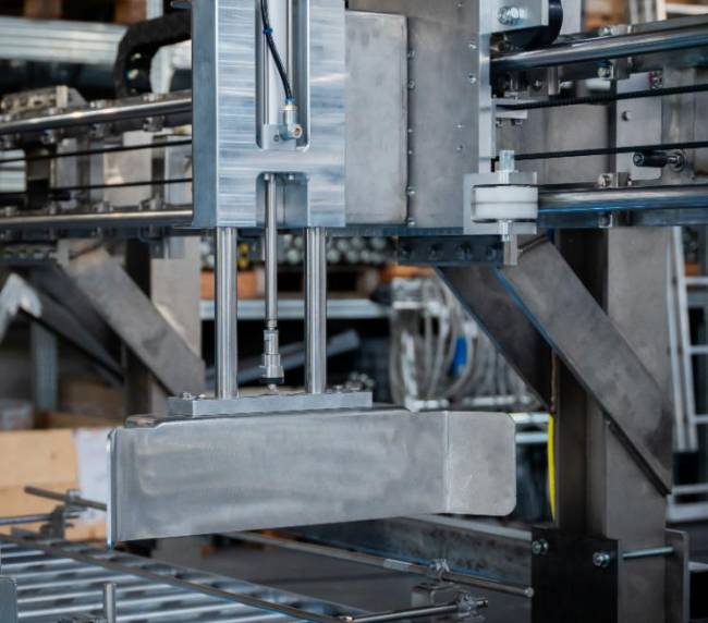 Electric pusher designed by Movin to transfer totes between motorized roller conveyors in an ATEX-rated zone