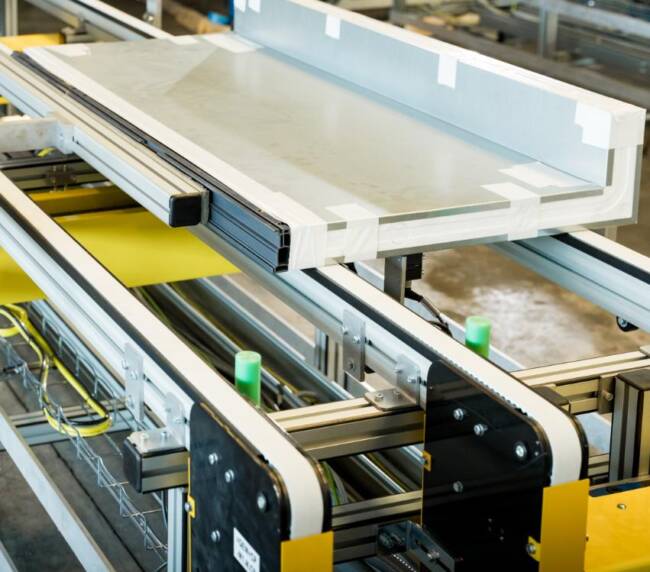 Foam sandwich panel for commercial refrigeration cabinets on a transfer conveyor, exiting the foaming stage ready for assembly