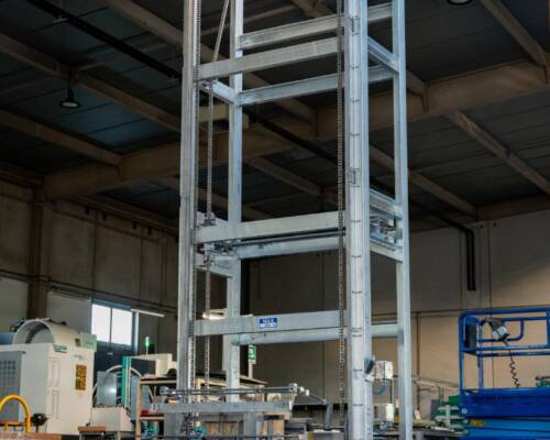 Industrial tilter designed to invert totes and pour powders into the mixer during the powder blending process