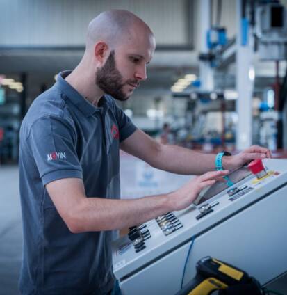 Movin specialized technician engaged in the development and configuration of software PLC and HMI on operator panel for the control of an industrial machine integrated in an automated assembly line.