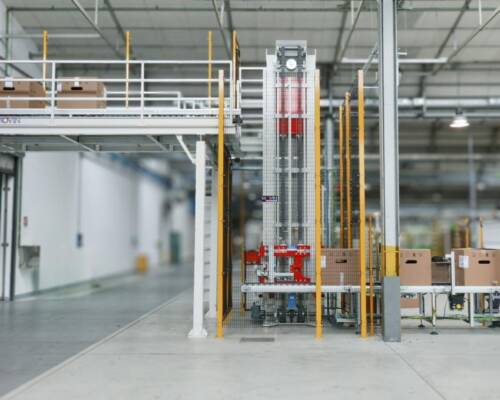 Packaged home appliances at end-of-line, transferred via a vertical lift from the production plant to the finished-goods warehouse for storage